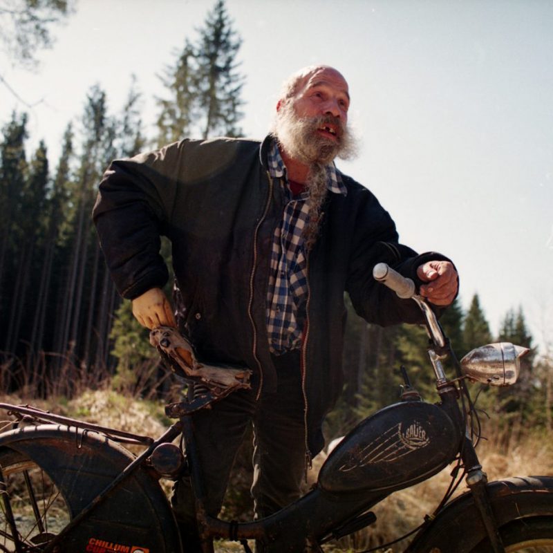 Bärtiger Mann mit Motorrad im Wald