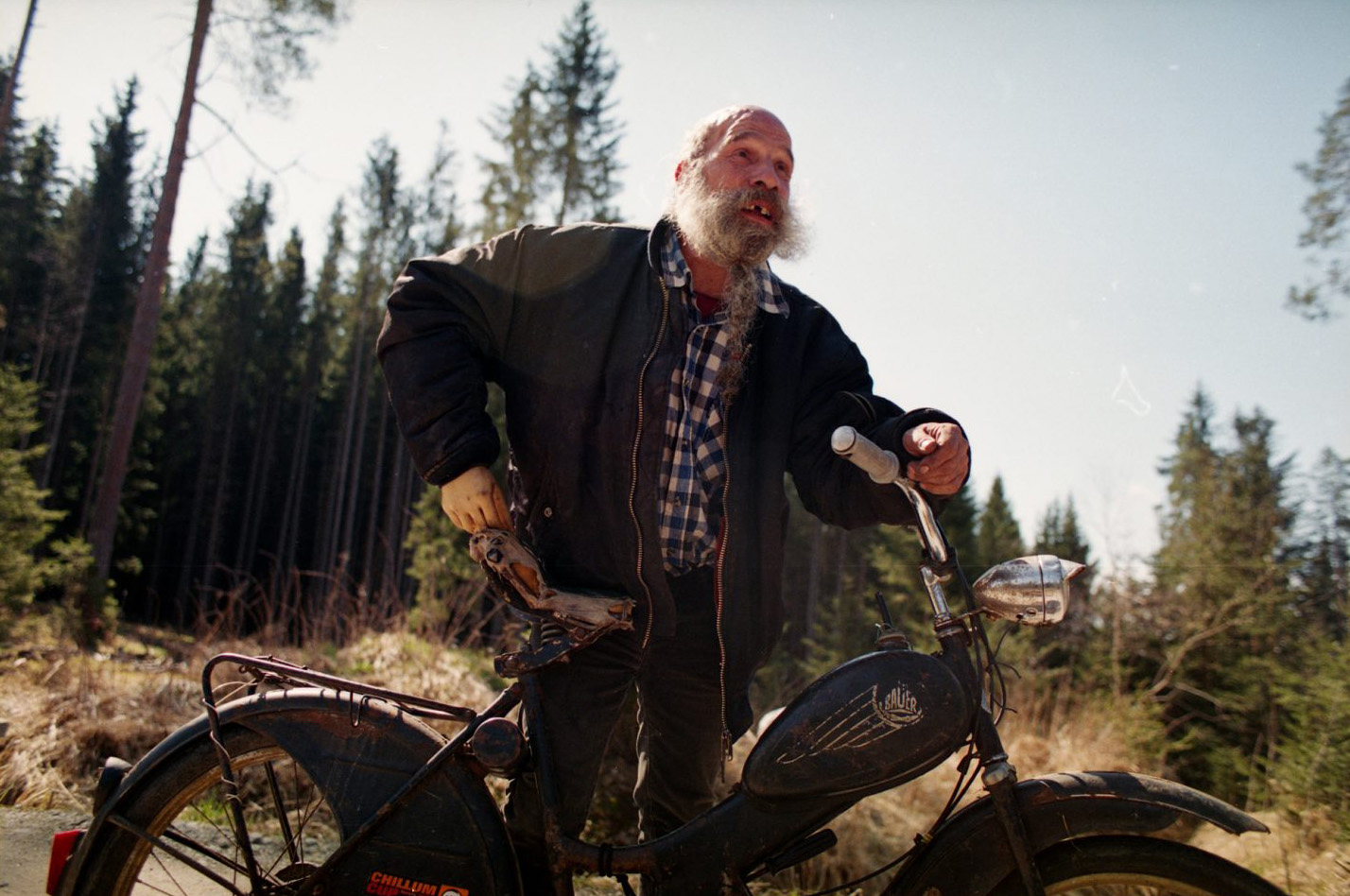 Bärtiger Mann mit Motorrad im Wald