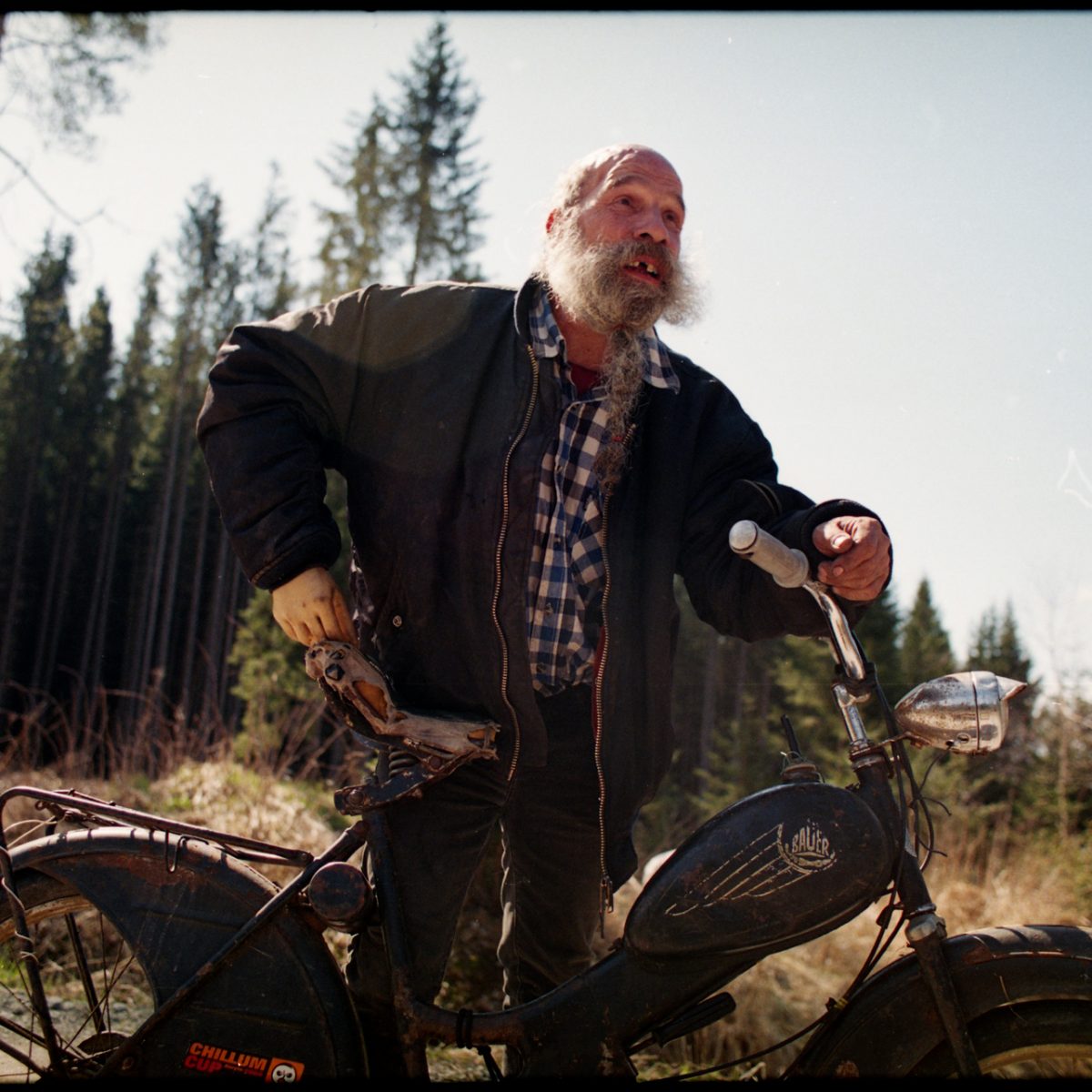 Bärtiger Mann mit Motorrad im Wald