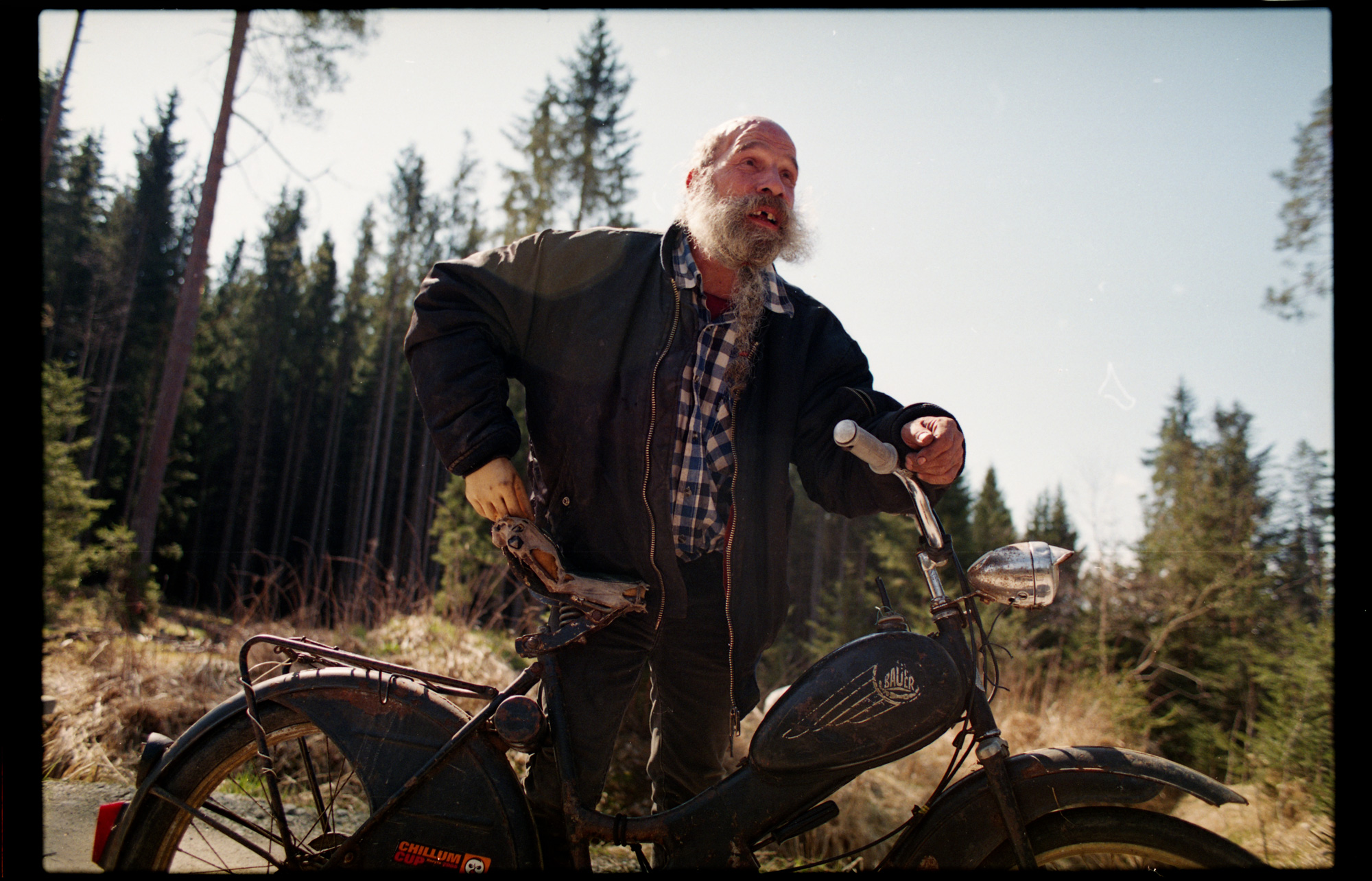 Bärtiger Mann mit Motorrad im Wald